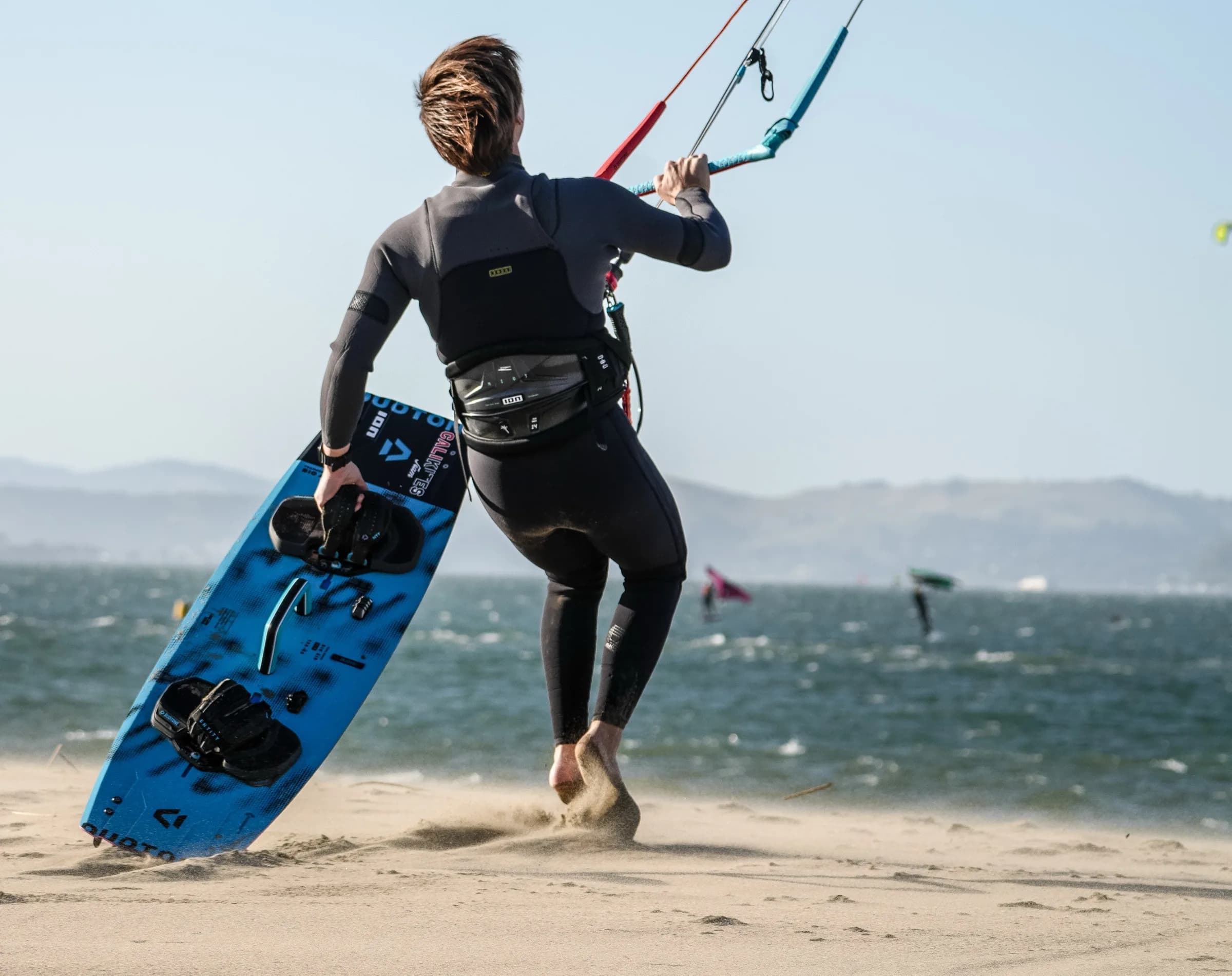 Kiteboarder walking out with board and bar at 3rd Avenue beach
